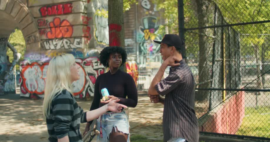 Three smiling friends chatting next to a skate park