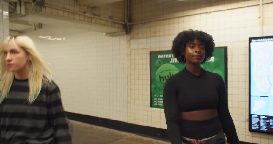 A blonde woman and a black woman are side by side walking toward the subway