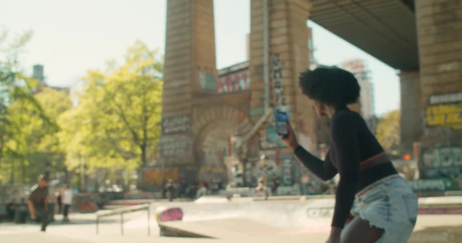Woman filming her colleague skateboarding in a square