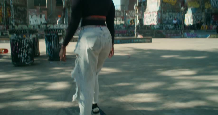 A black girl rides her skateboard in a city park