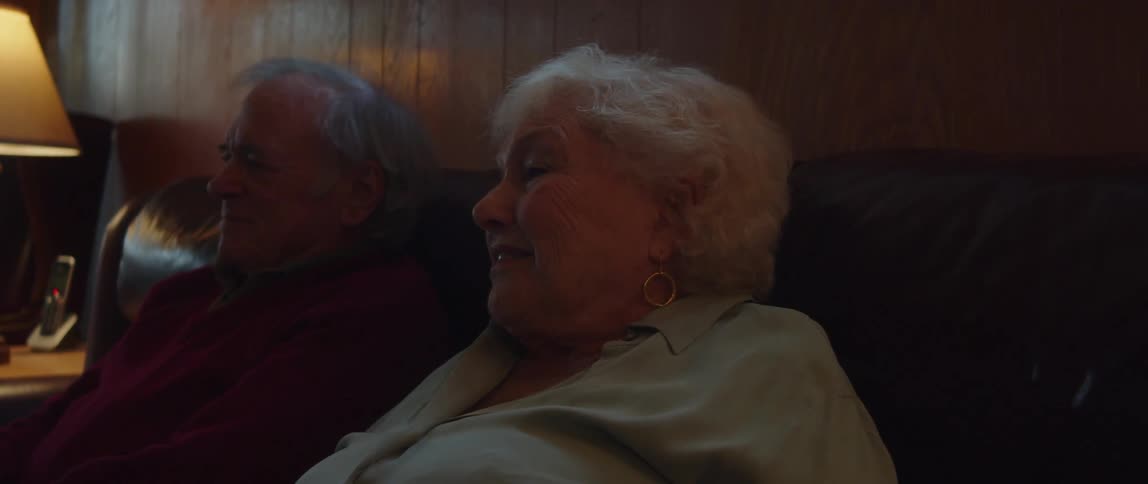 Elderly couple sits on the couch in a living room and talks together