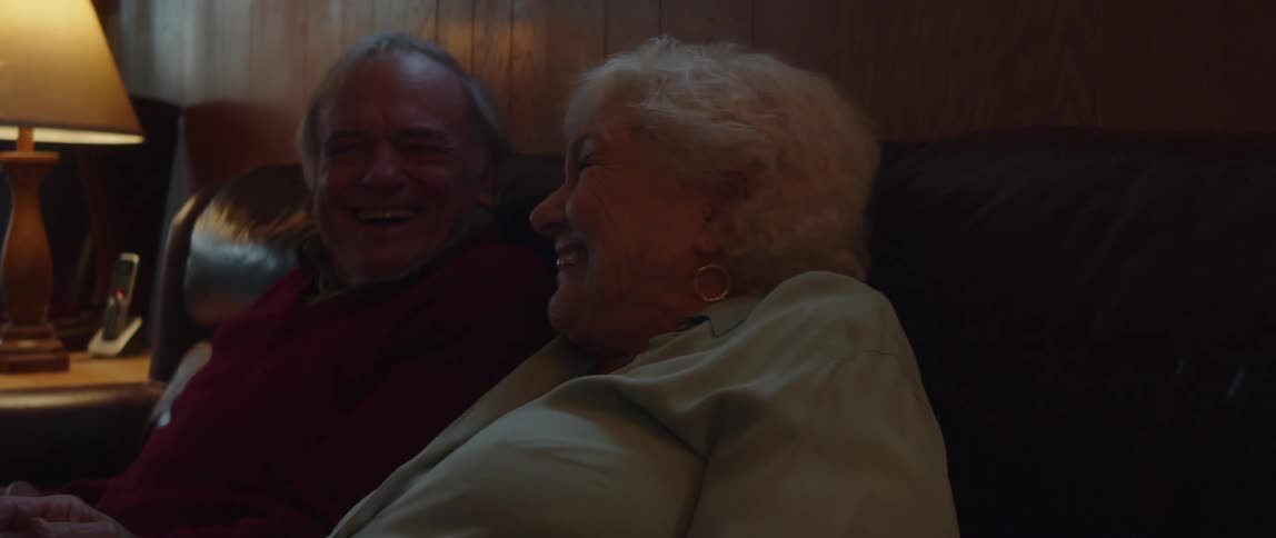 Elderly couple clap and laugh together while watching tv