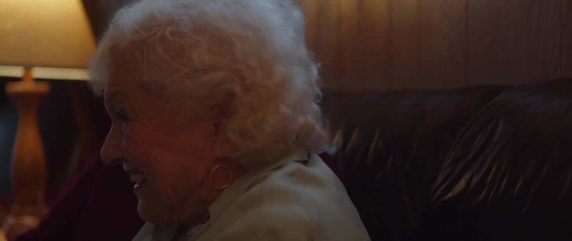 An elderly couple sitting on the couch at home having fun watching television together