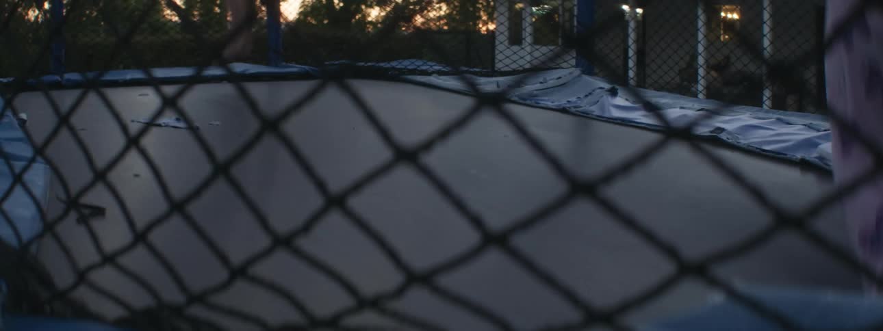 Girls play together on a trampoline in the backyard as red tints the horizon