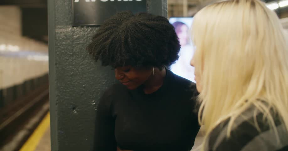 Two skater girls chatting while waiting for the subway train