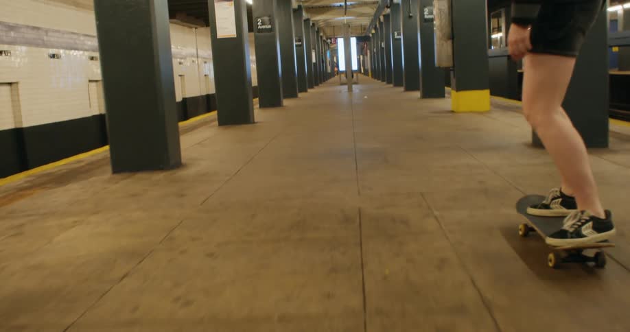 Two females skateboard through a subway terminal