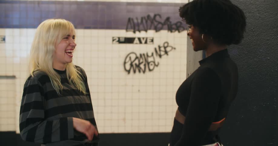 Two women talk and laugh in the subway