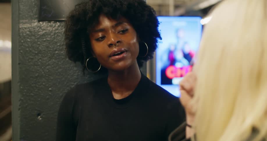 A black teenager talks to a blonde girl in a subway terminal