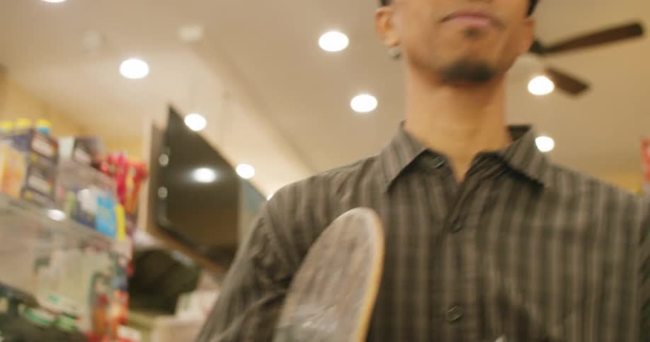 Man in a convenience store buying and holding his skateboard