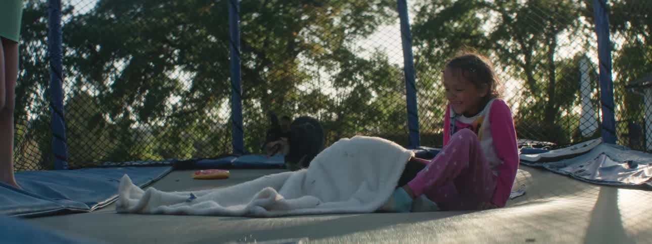 Two children play on a trampoline with their dogs