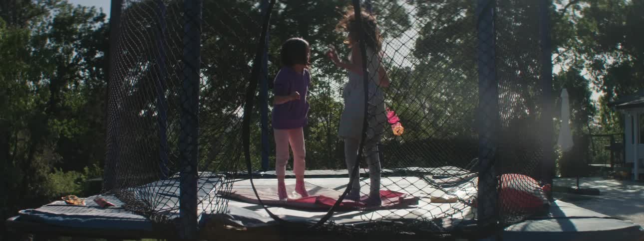 Two little girls jumping on a trampoline