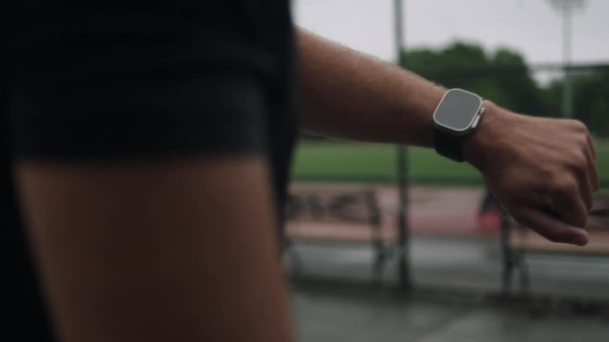 Standing in a park a man lifts his wrist to check his smartwatch
