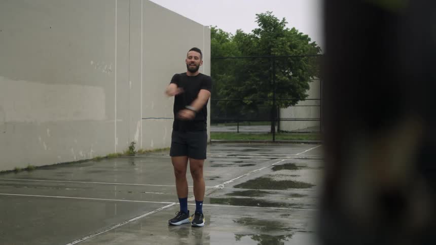 Man in an empty parking lot stretching his arms