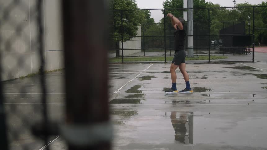 A man wearing shorts stretches on a court