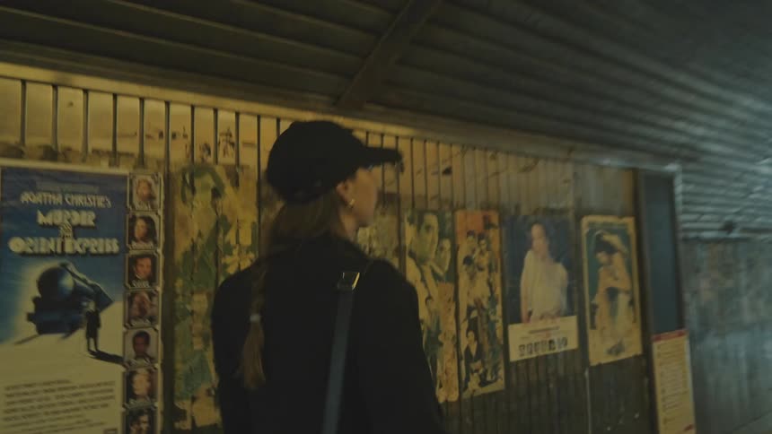 Woman in a cap and coat passing through a tunnel through the city