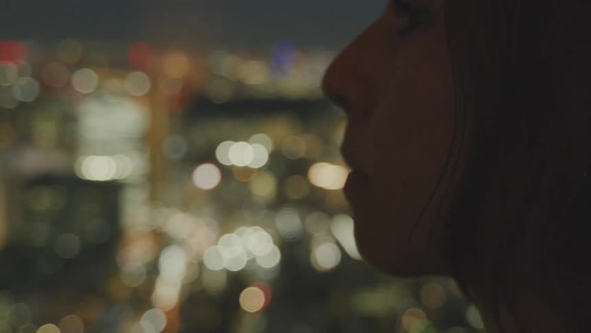 The face of a woman who is looking at a city and at night it is all lit up