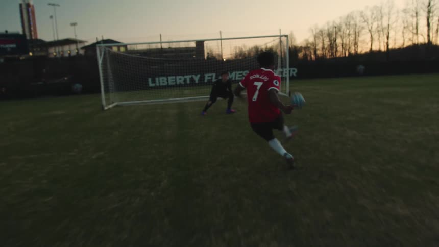 A soccer player in a red jersey scores a goal