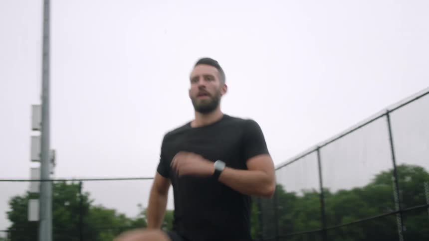A man does cardio on an outdoor court in a city