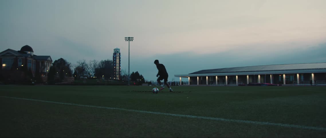 Boy on a soccer field doing warmup movements with a soccer ball at his side