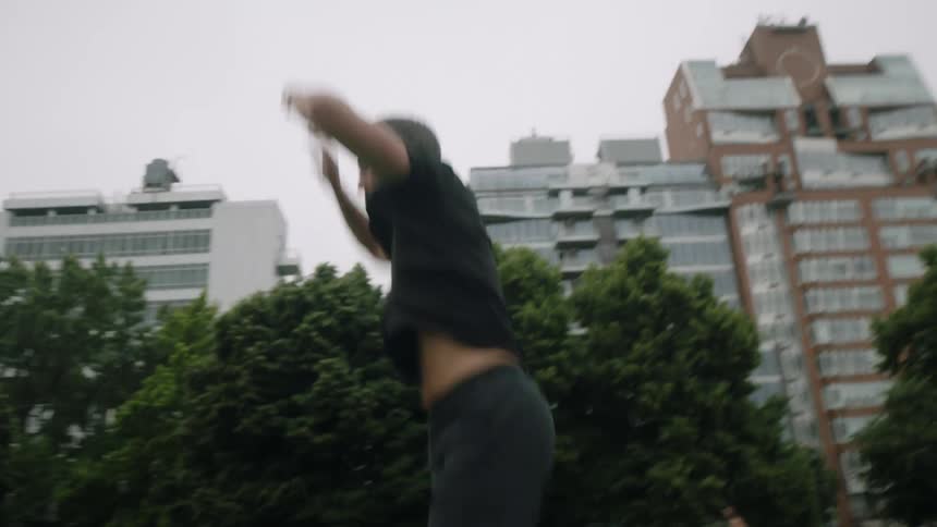 A man is doing burpees in the park on a cloudy day