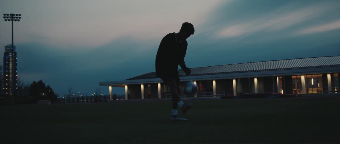 A black athlete practices kicking a soccer ball on a field