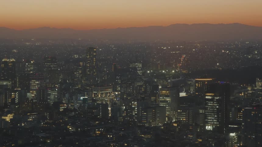 Panorama of a metropolis with illuminated buildings with the silhouette of mountains on the horizon