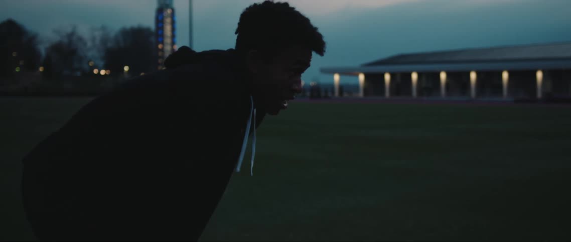 Silhouette of a young tired teen standing field near the city during sunset or sunrise