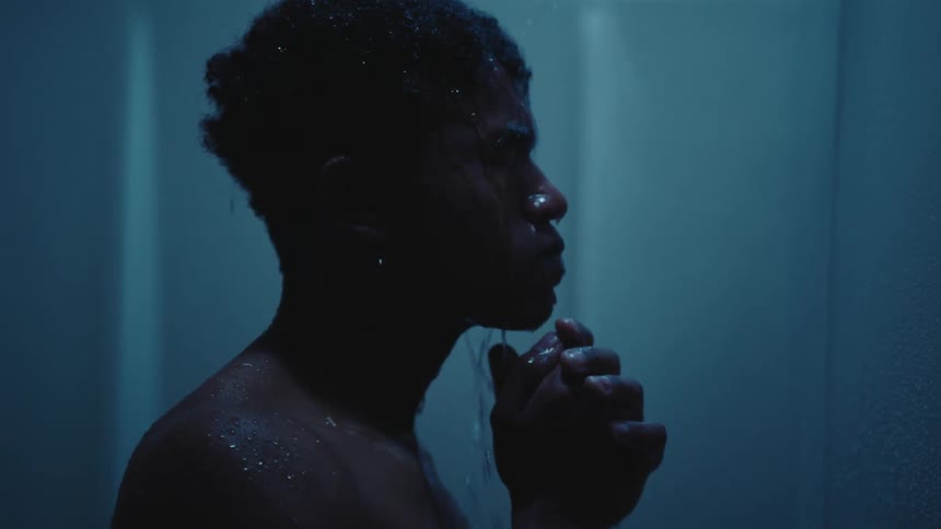 A man takes a shower letting the water hit his face