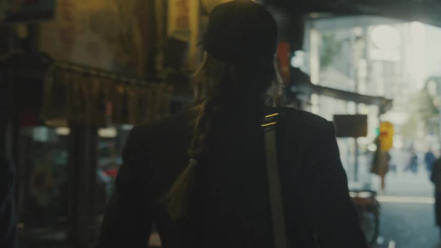 Woman in a cap walking through a gallery in a tunnel on a city sidewalk