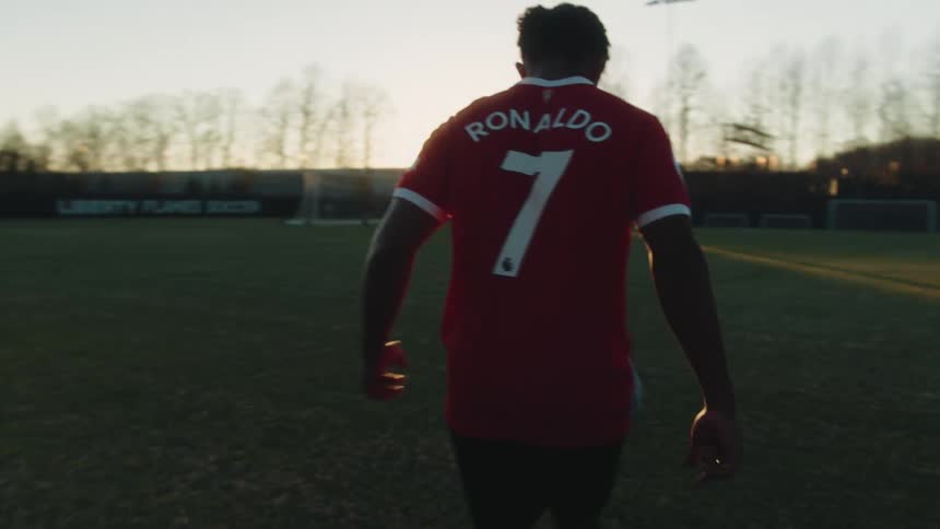 Young man on a soccer field hitting kicks and doing freestyle with the ball with a sunset on the horizon