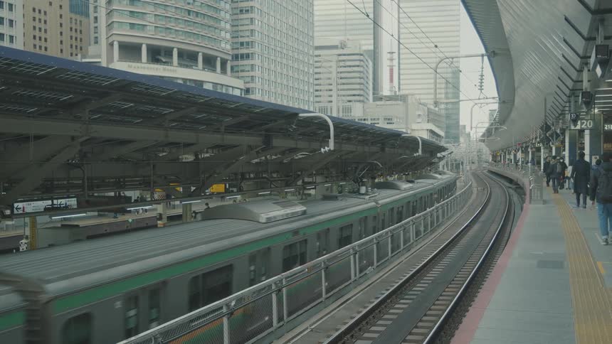 Train passing through a subway station with several pedestrians walking