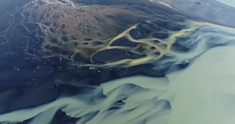 Natural landscape of a coastal area where water meets land with distinct patterns of sand and canals