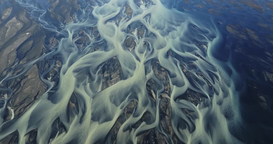 Frozen rivulets of white and blue contrast with textured gray surface