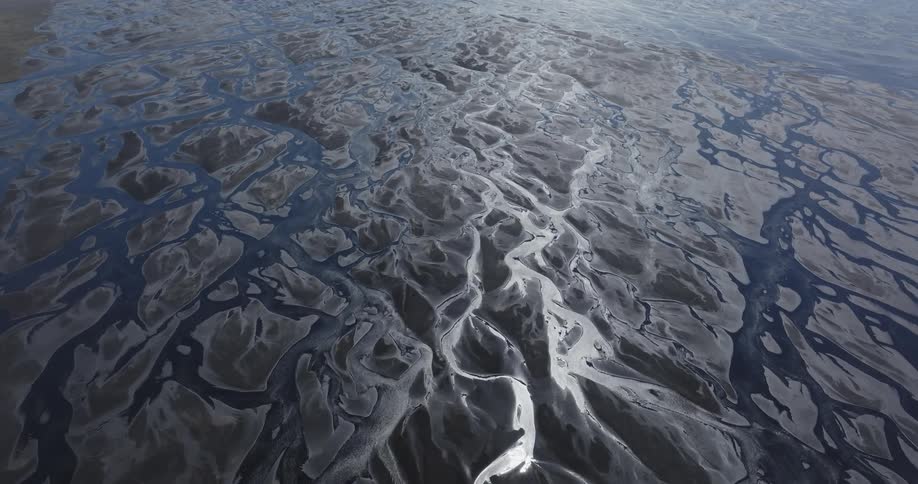 Vast landscape of a riverbed with intricate patterns of ridges and depressions carved into the surface