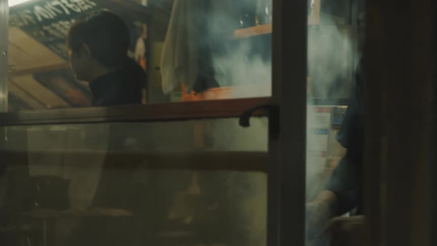 Two people making food with a lot of white smoke next to a small glass window
