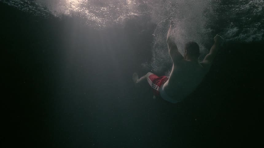 Body falling into a submerged ocean with a sunlight