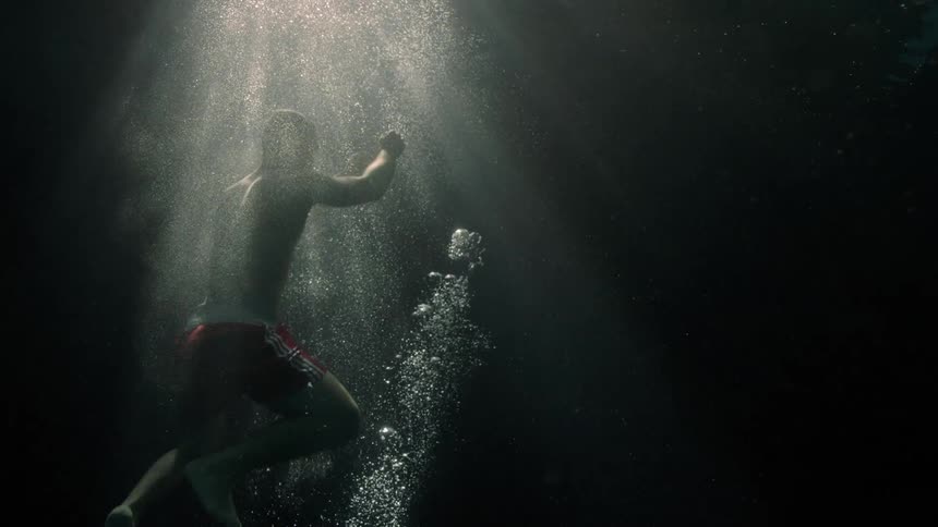 Man submerged inside the ocean rising towards the surface