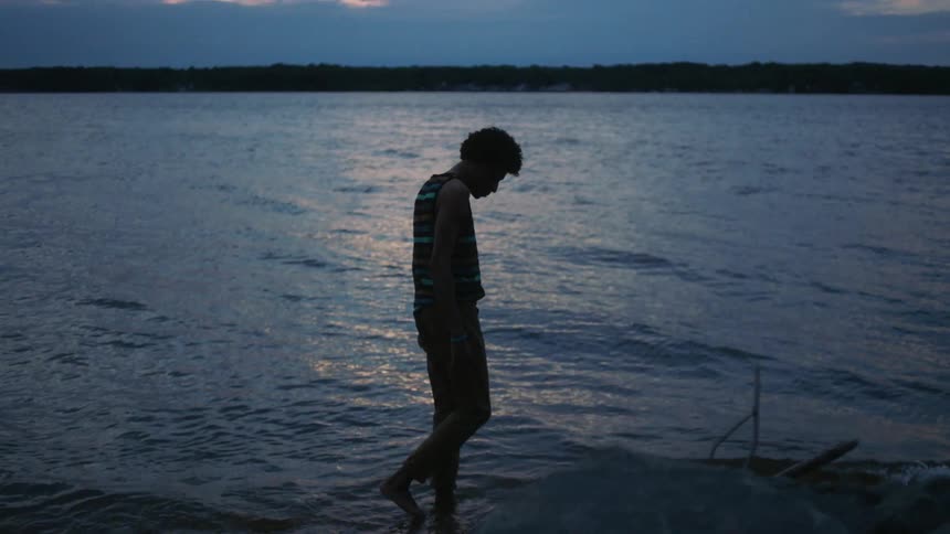 Silhouette of a man walking next to a lake
