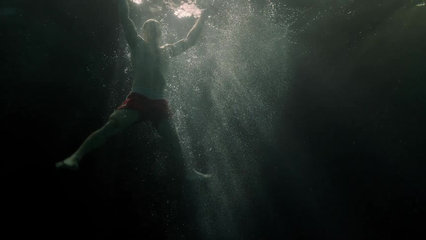 Man swimming towards the surface while submerged by the ocean