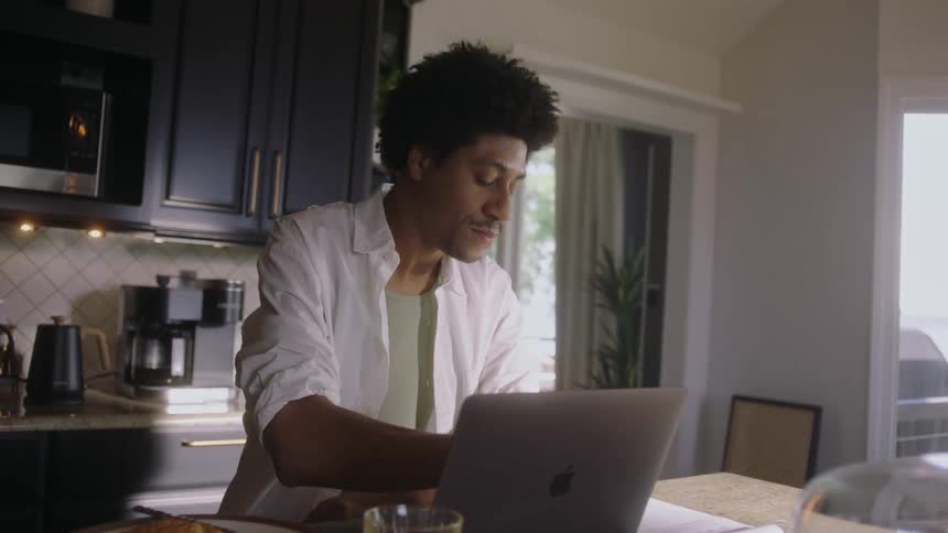 Man sitting in the kitchen working on a laptop