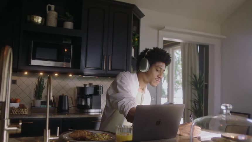 A man sways to music while working on his laptop at home