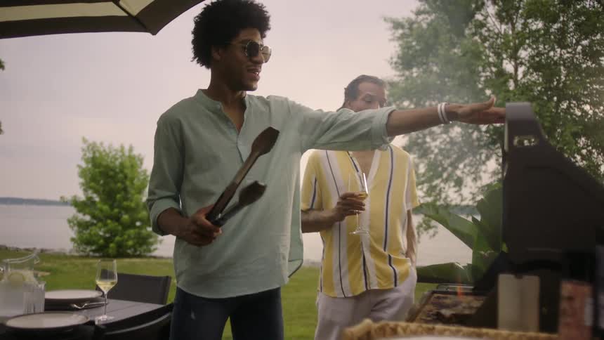 Two friends in a backyard with one of them preparing a barbecue