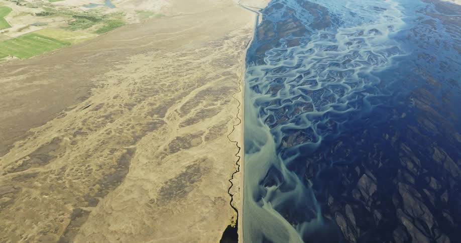 Arid dry landscape on the left and a large deep blue body of water on the right