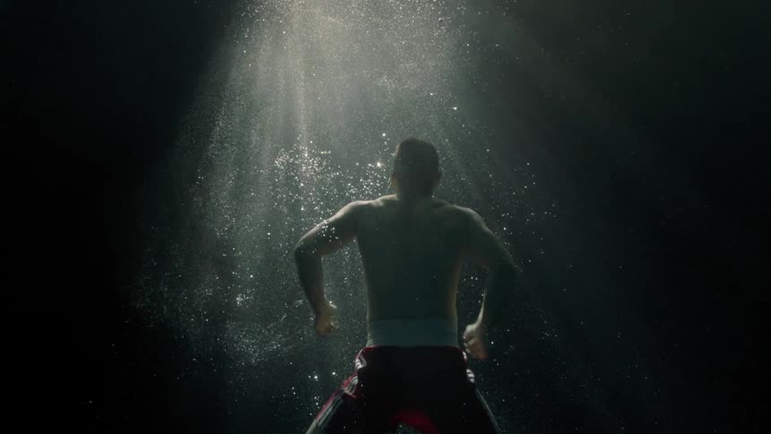 A man swims to the surface of the water