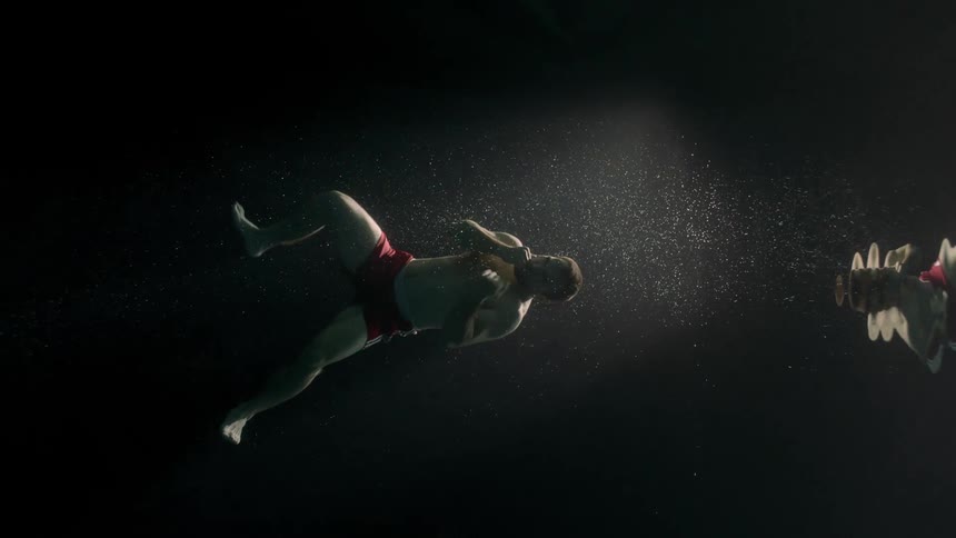 Man in swimming trunks submerged in the ocean throwing training punches