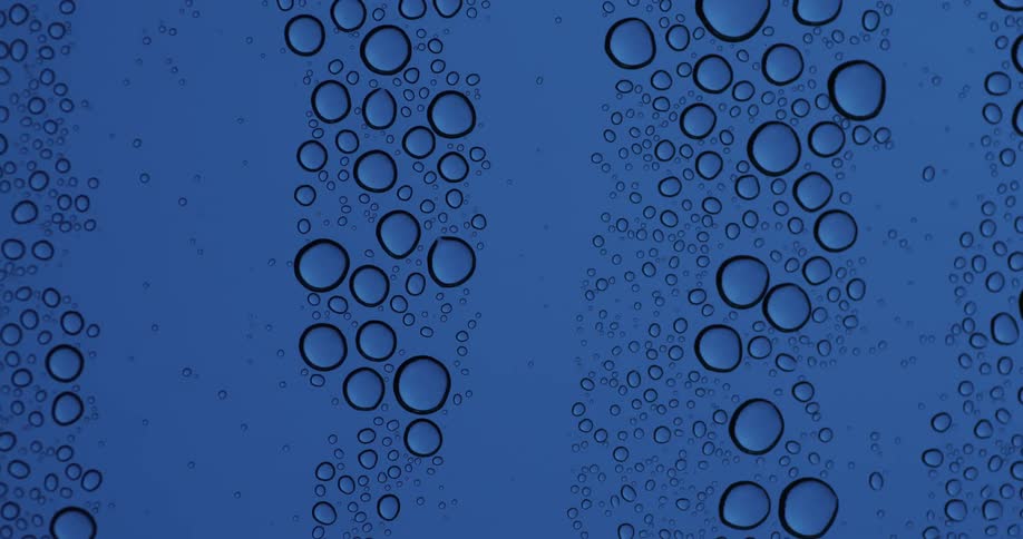 Drops of condensation on a blue surface as a droplet runs down the surface