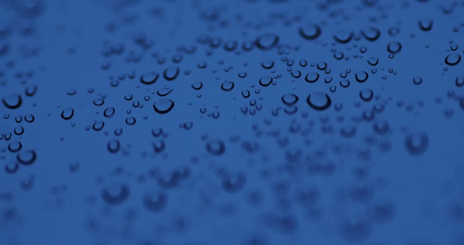 A closeup of water droplets on a surface with a blue hue
