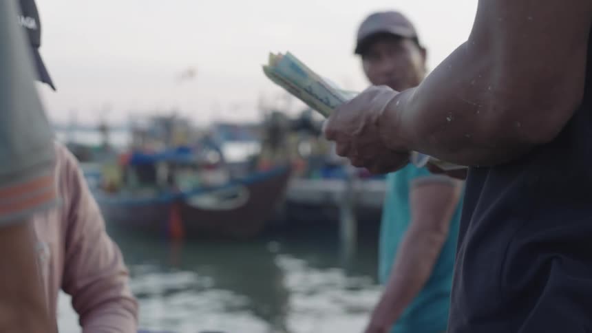 Person receiving and counting money bills at the seaside