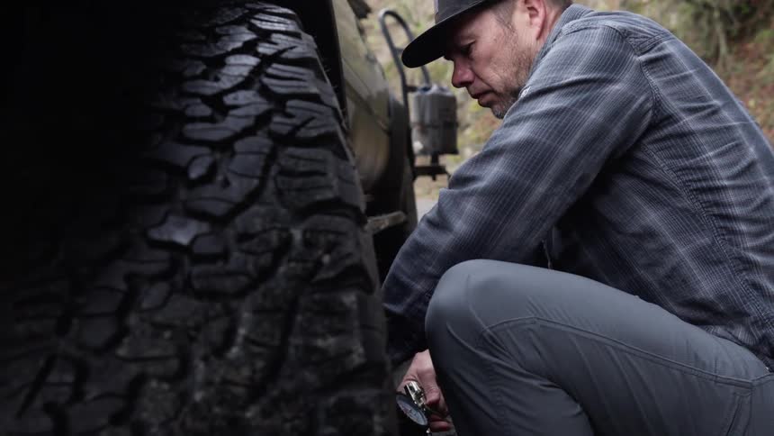 Man going towards the tire and removing it from a truck
