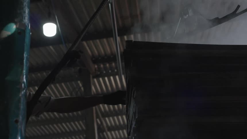 Arm of a person inside a factory stopping a metal sheet that evaporates steam
